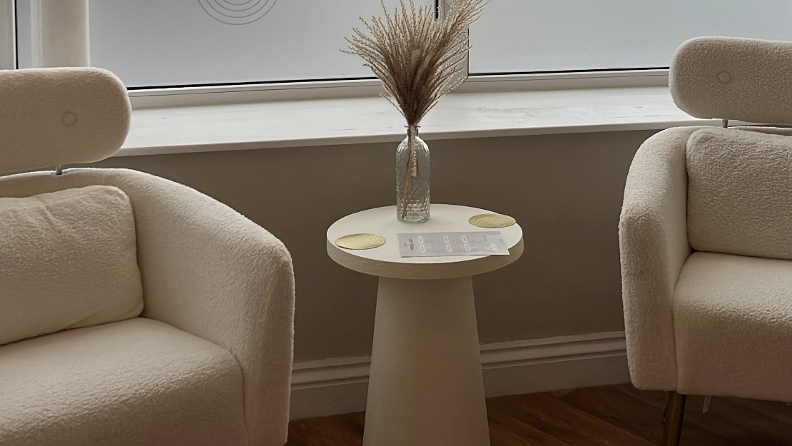 Two cream armchairs and a side table by the frosted window