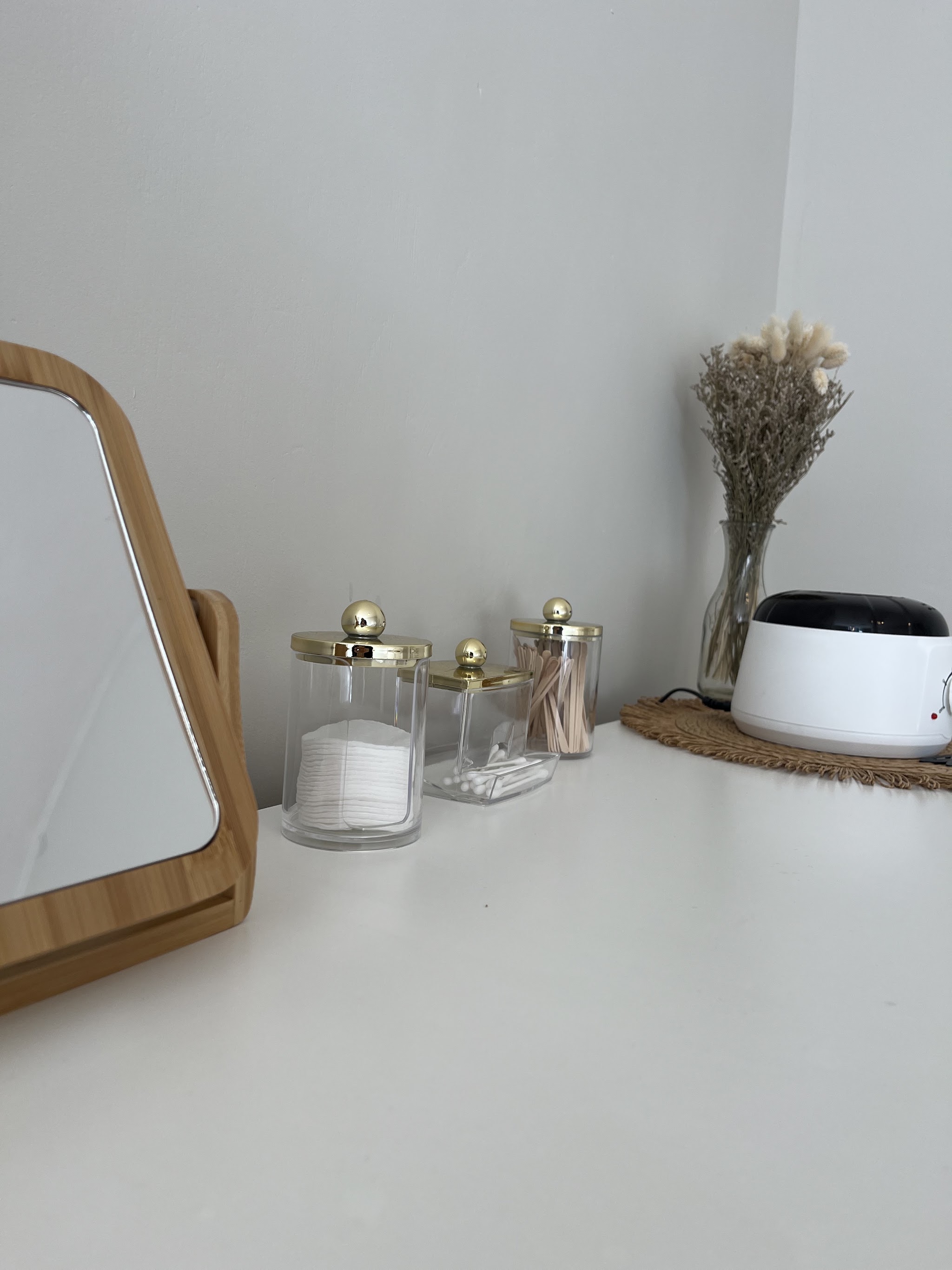 A workstation with a wooden mirror, glass jars and dried flowers